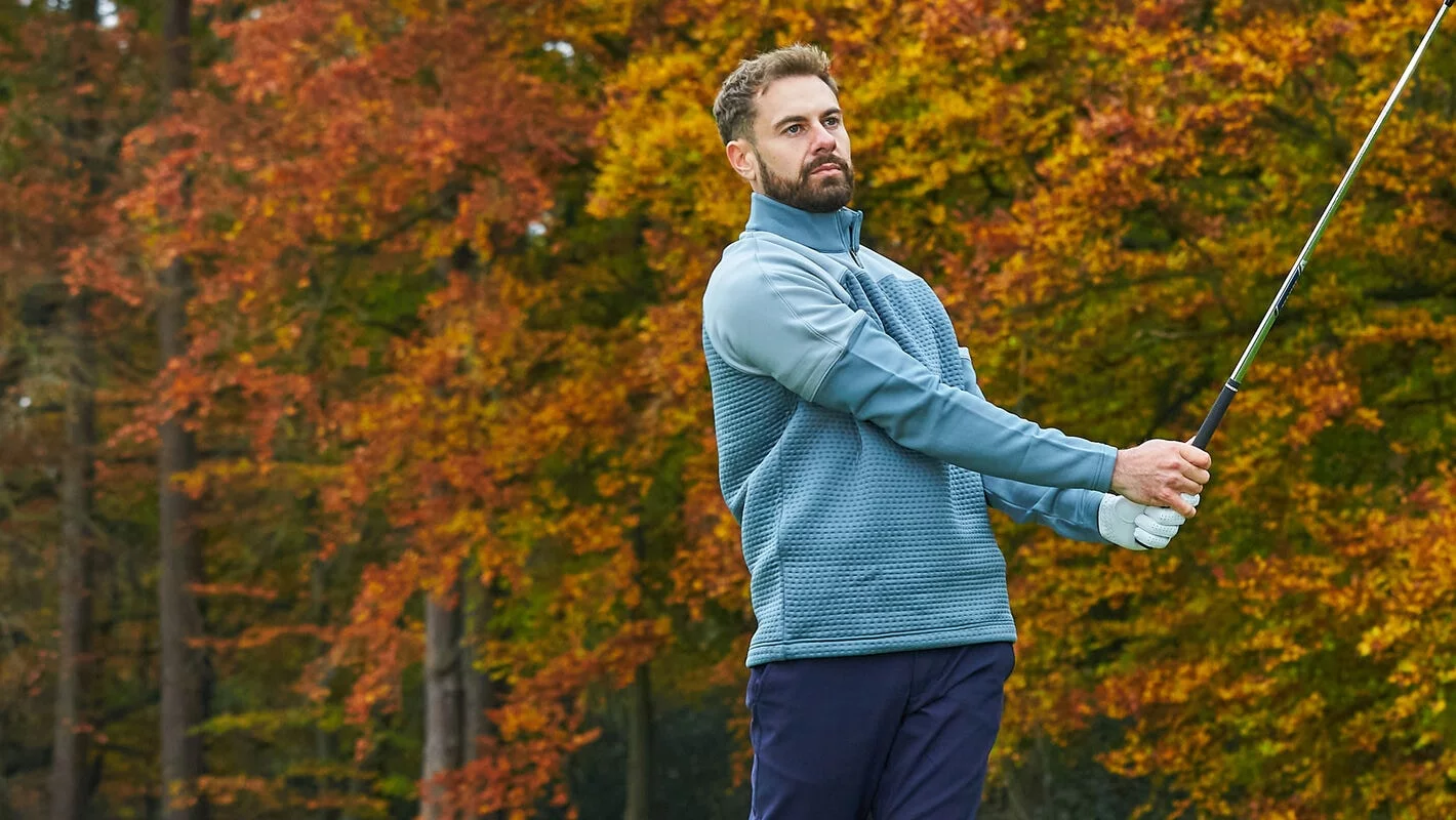 Golfer wearing warm winter golf clothing on a frosty golf course